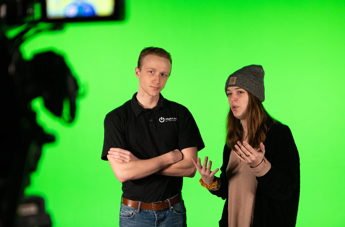 Two individuals speaking on a green screen film set